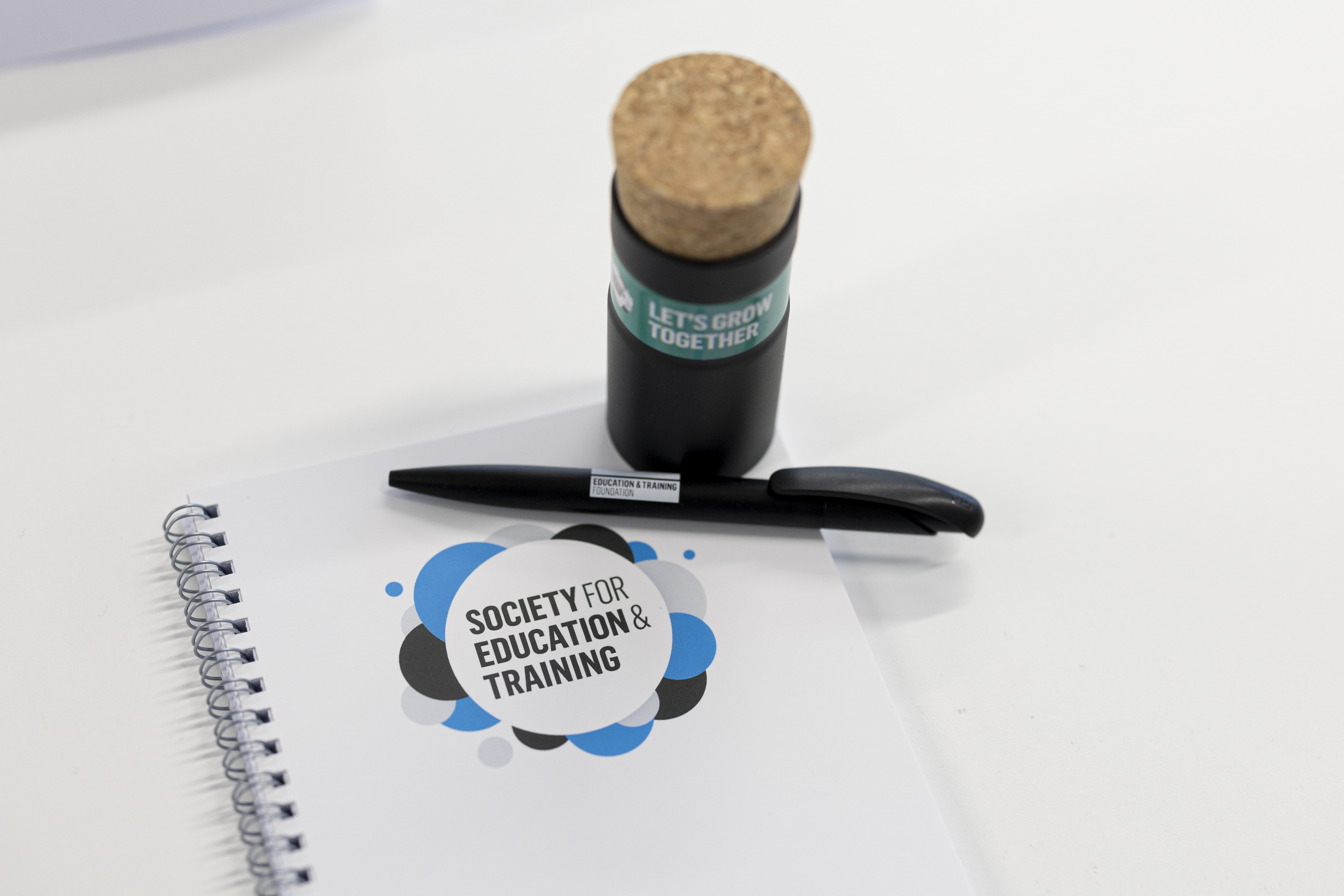 A notebook that says Society for Education and Training with a pen